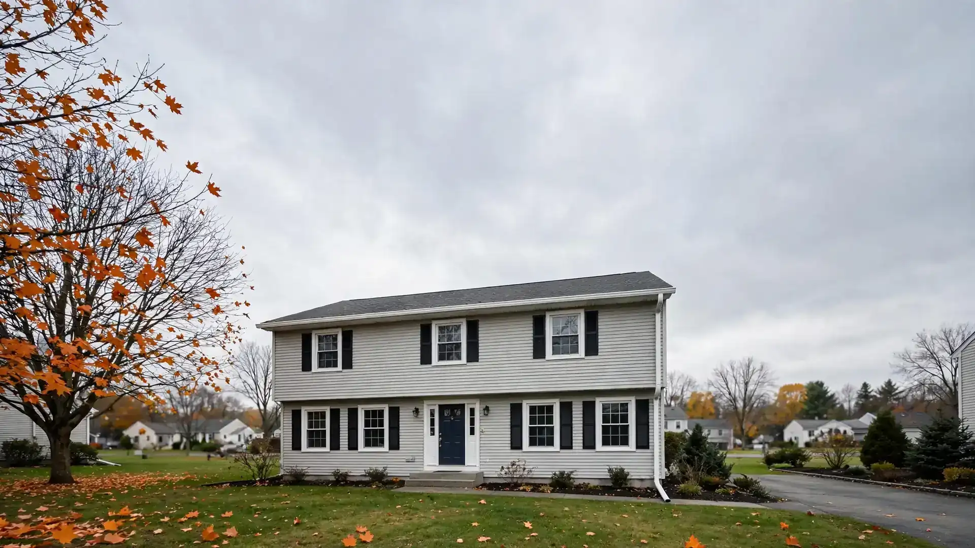 New white aluminum gutter run along the roof edge of a two-story house in early autumn